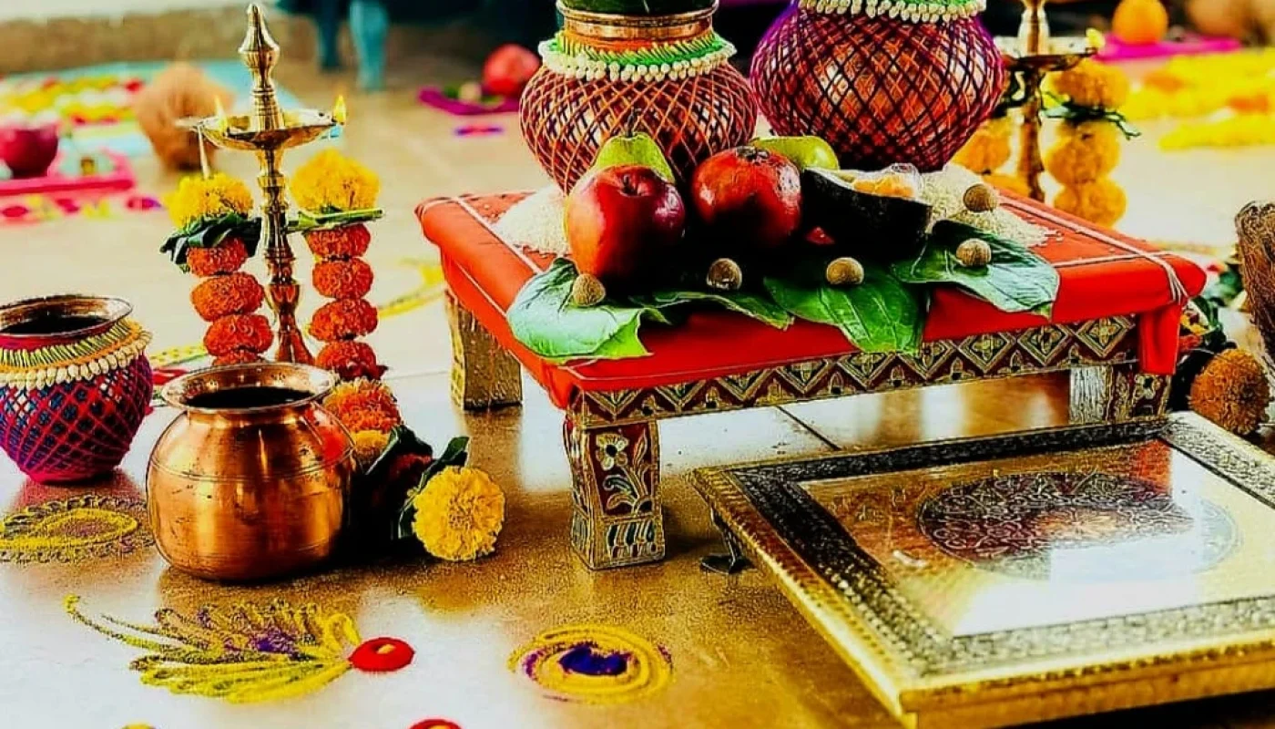 Two beautifully decorated kalash with fresh mango leaves and marigold flowers, placed on a carved wooden chowki with a colorful rangoli traditional Kalash Sthapana Puja setup.