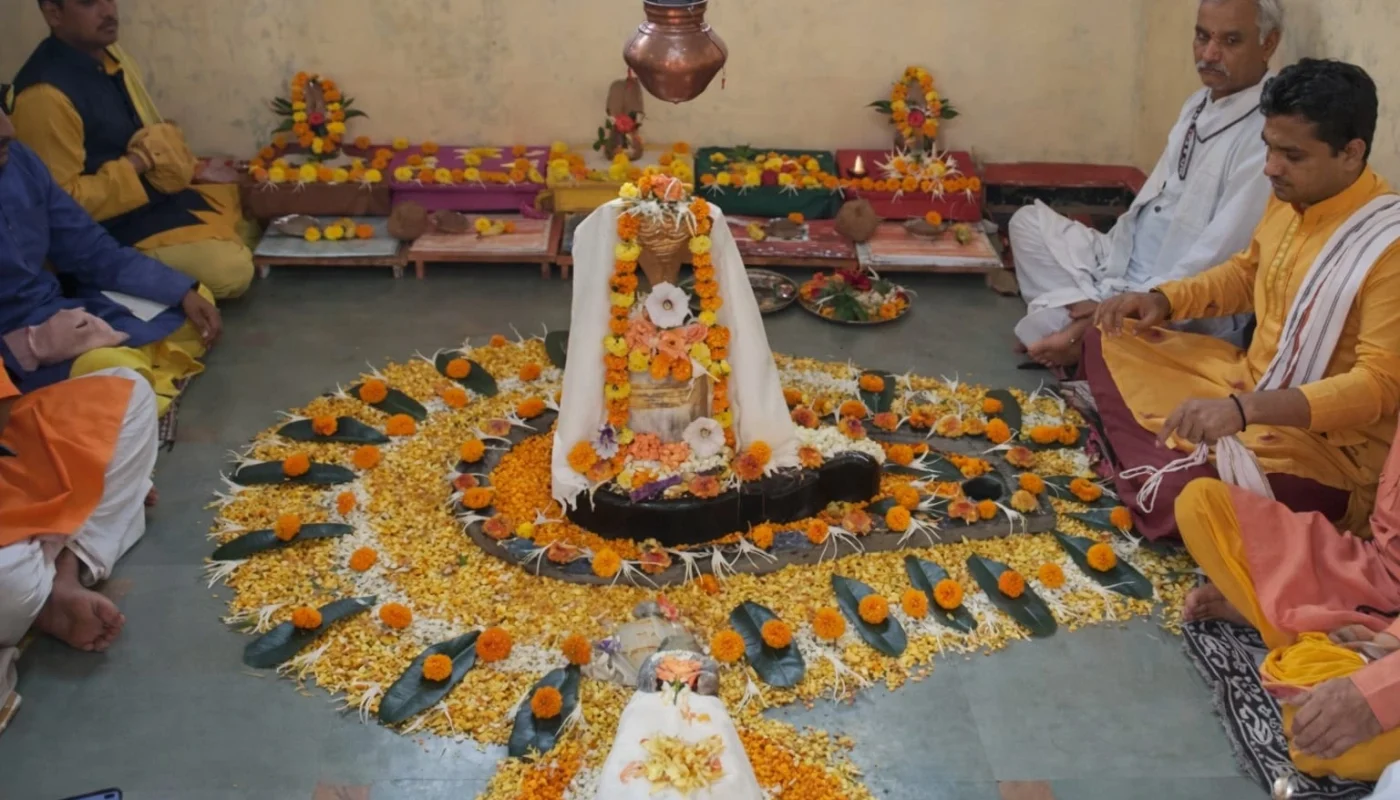 Mahamrityunjaya Jaap ritual at Trimbakeshwar Shivling decorated with marigold flowers, Abhishek Kalash above, and pandits seated around performing Jaap