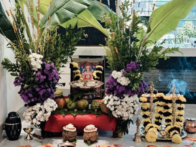 Grand Satyanarayan Puja at a Mumbai apartment with traditional banana leaf arrangements, purple and white flowers, incense, and a Vishnu deity photo beautifully arranged for the home puja.